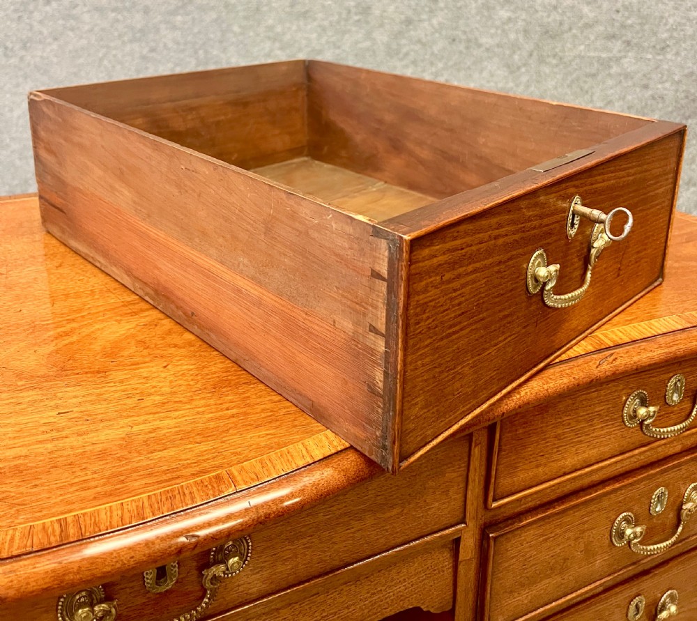 A George III mahogany kneehole desk featuring multiple drawers with brass swan-neck handles, a central recessed cupboard, and bracket feet. View XI