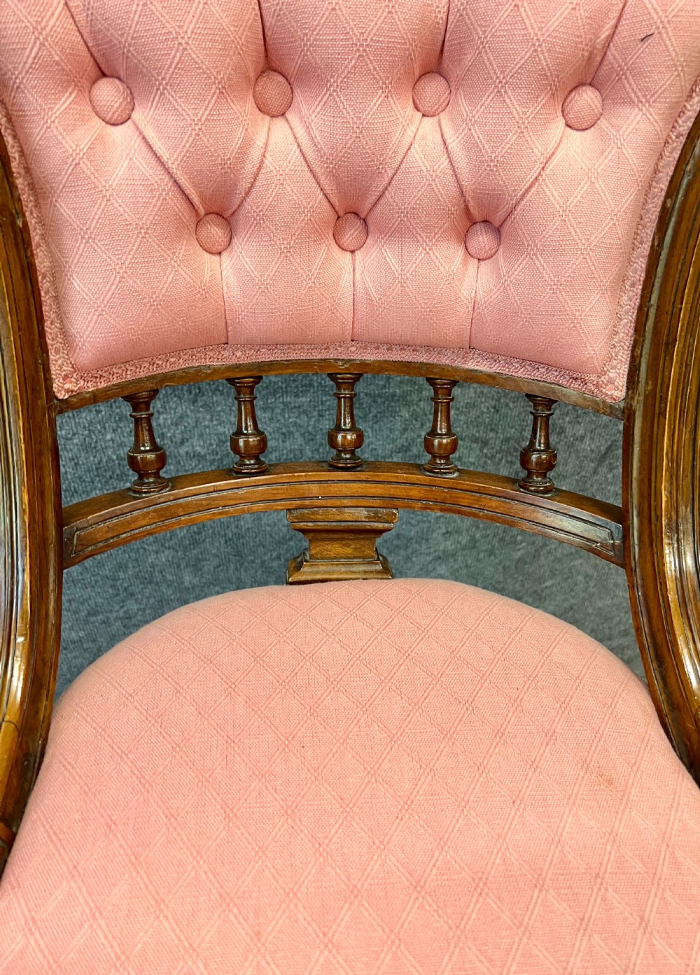 A late Victorian dark walnut revolving music chair featuring a pink button-tufted upholstered backrest, turned spindle gallery, round padded seat, and turned legs with cross stretchers. View VII