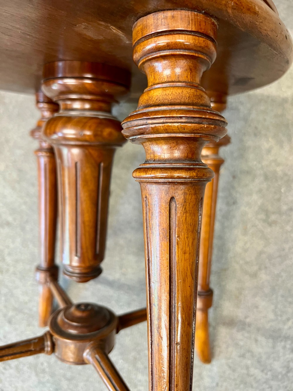 A late Victorian dark walnut revolving music chair featuring a pink button-tufted upholstered backrest, turned spindle gallery, round padded seat, and turned legs with cross stretchers. View VIII