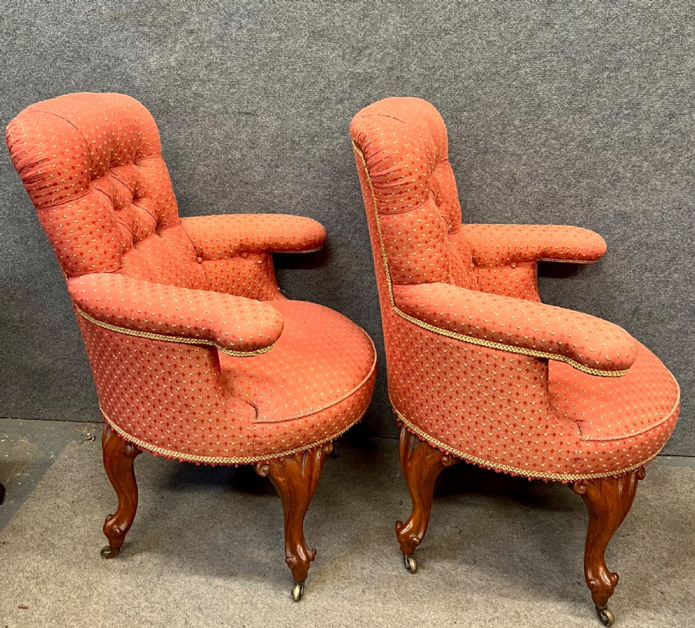 A pair of Victorian tub armchairs featuring patterned terracotta fabric, deep button tufting, and carved timber cabriole legs with brass castors. View II