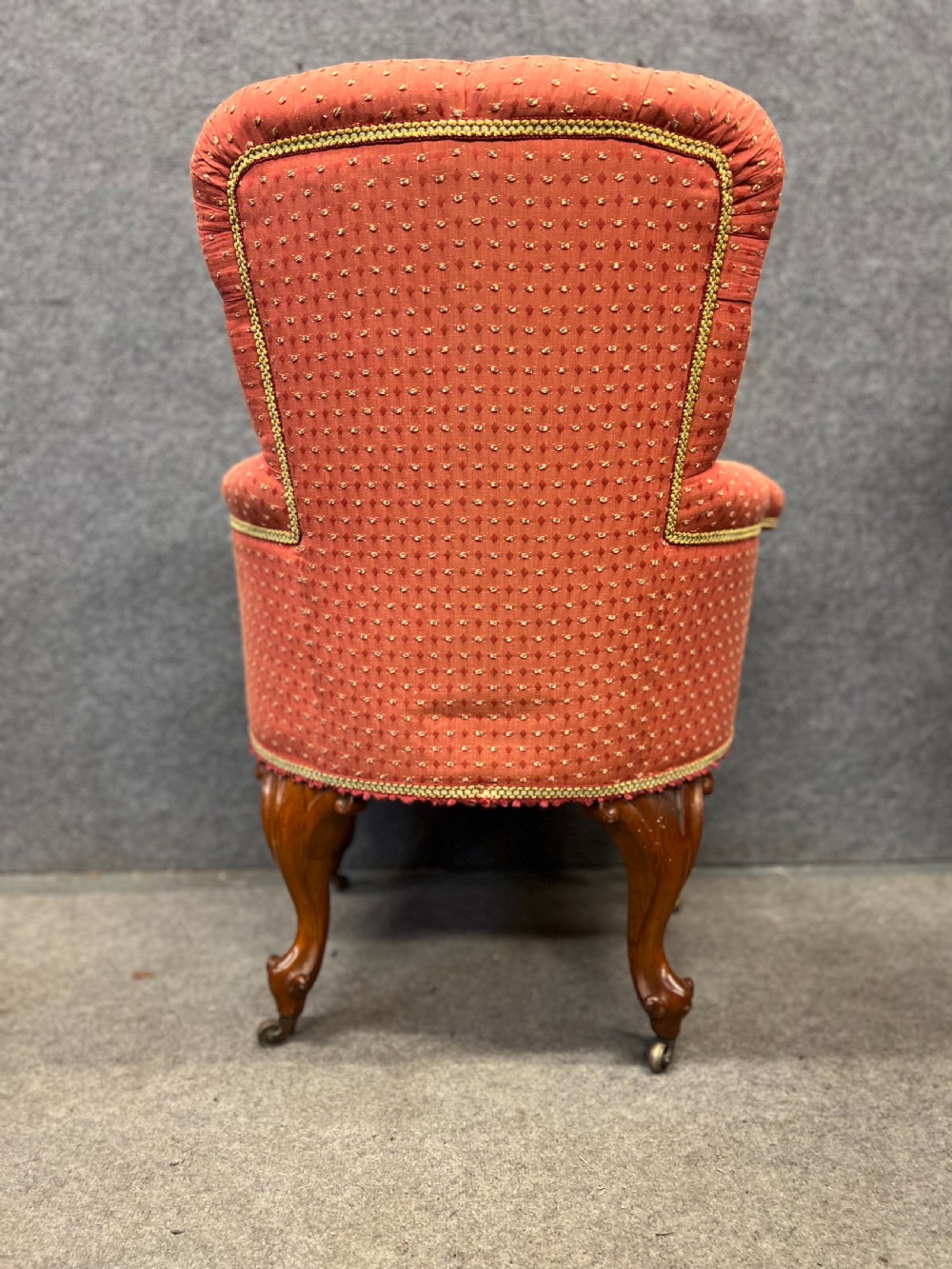 A pair of Victorian tub armchairs featuring patterned terracotta fabric, deep button tufting, and carved timber cabriole legs with brass castors. View VI