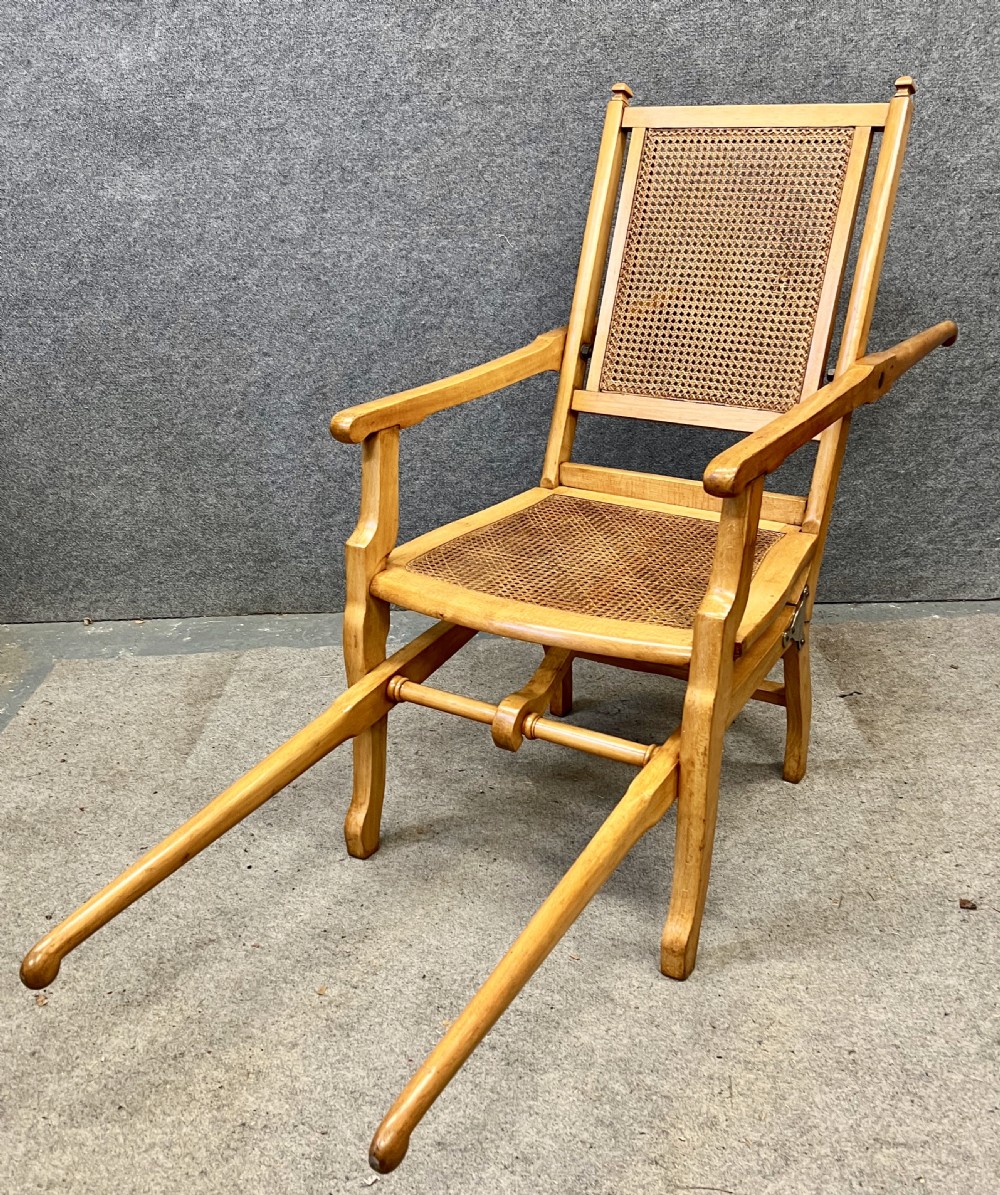 An antique French First World War campaign invalid chair constructed from light wood with woven cane panels and extending transport handles.