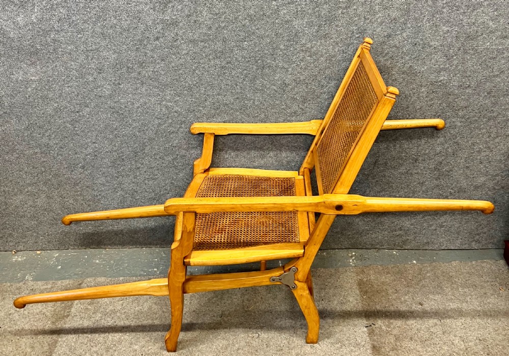 An antique French First World War campaign invalid chair constructed from light wood with woven cane panels and extending transport handles. View III