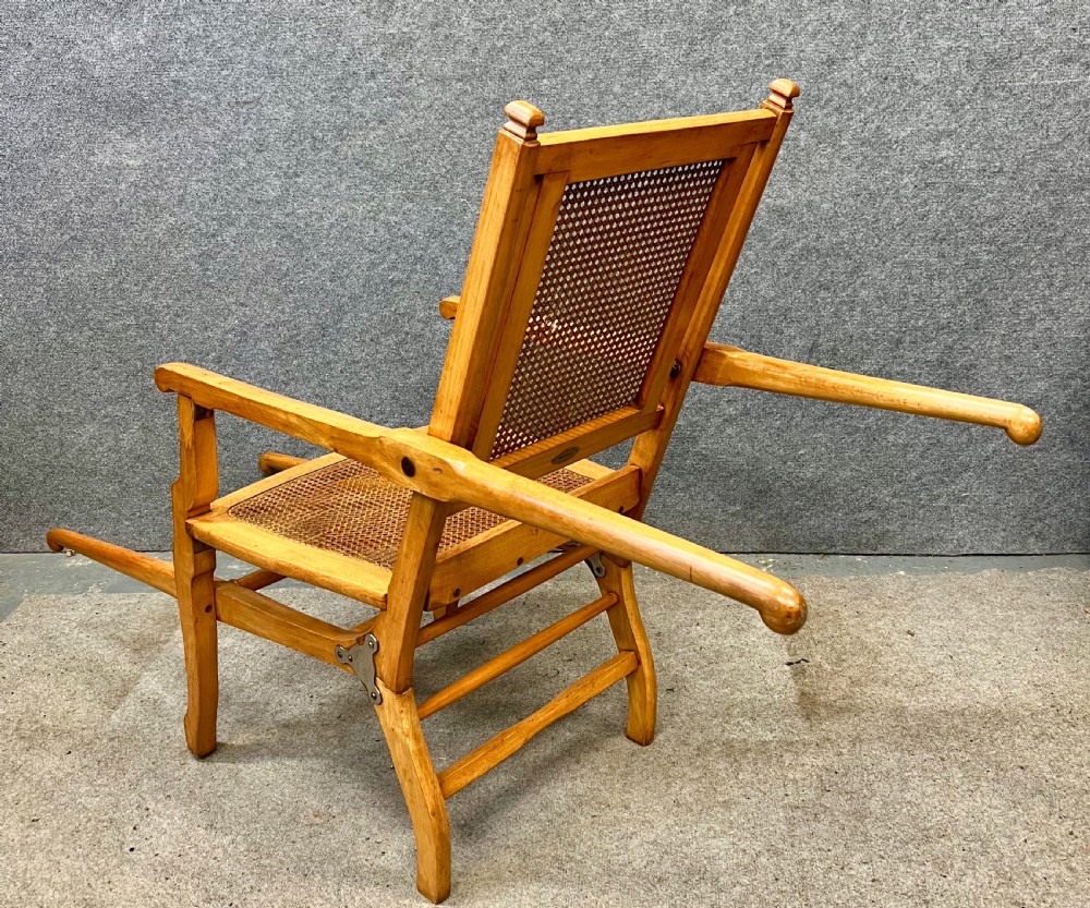 An antique French First World War campaign invalid chair constructed from light wood with woven cane panels and extending transport handles. View V