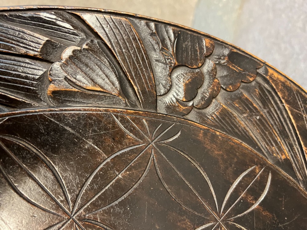 A circular dark ebonised wooden occasional table featuring a carved geometric top border with iris motifs, curved legs, and a small carved undertier shelf. View VIII