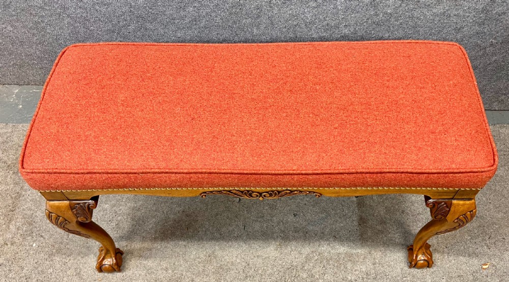 An upholstered window seat featuring a terracotta red fabric cushion with brass stud detailing, supported by carved walnut cabriole legs ending in claw and ball feet. View VII