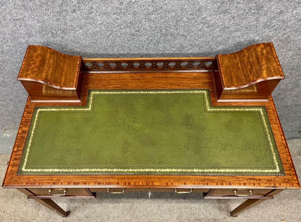 An Edwardian mahogany ladies writing desk featuring a green leather inset writing surface, inlaid crossbanding, three drawers with brass handles, twin raised stationery boxes, and tapered legs on castors. View III