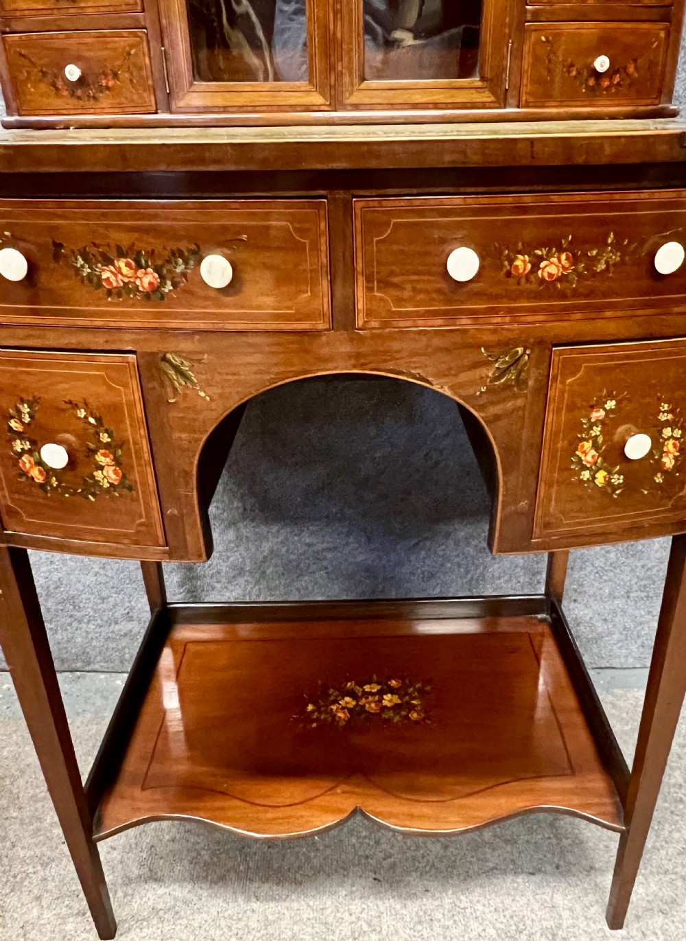 An Edwardian bonheur du jour desk crafted from polished dark wood, featuring a green leather writing surface, painted floral details, a upper superstructure with a painted portrait panel, small drawers, and a central glazed cabinet. View VIII