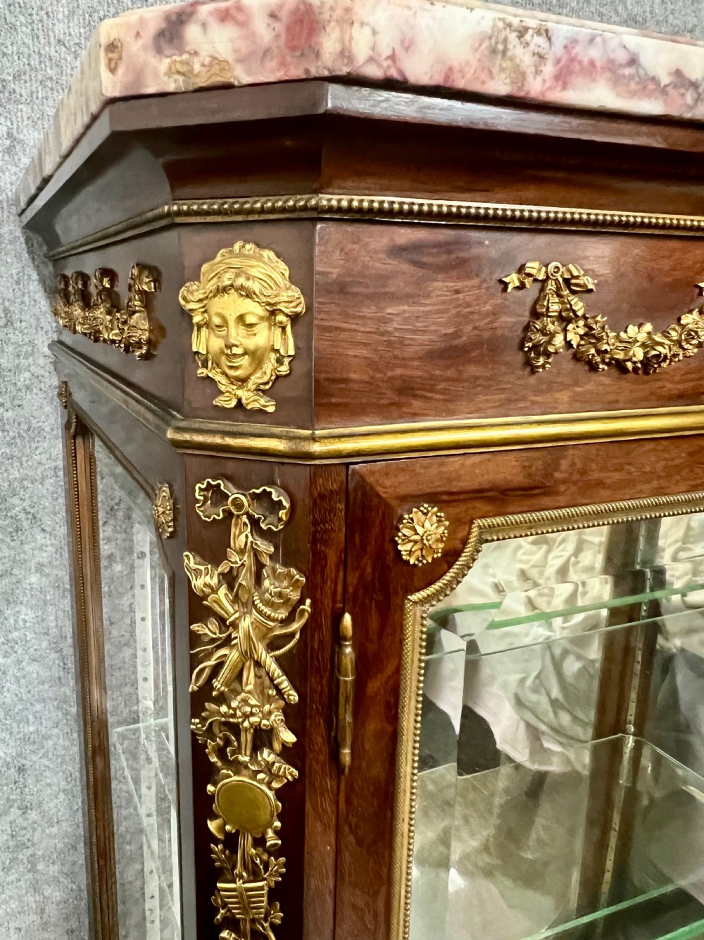 An antique French kingwood vitrine display cabinet featuring glazed double doors, gilt bronze ormolu mounts, glass shelves, a mirrored interior back, and a marble top. View II