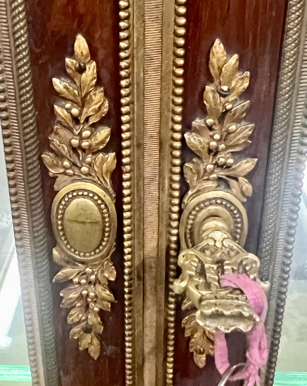 An antique French kingwood vitrine display cabinet featuring glazed double doors, gilt bronze ormolu mounts, glass shelves, a mirrored interior back, and a marble top. View IV