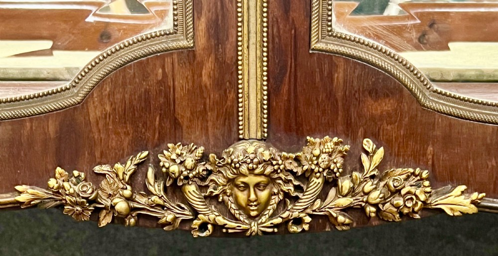 An antique French kingwood vitrine display cabinet featuring glazed double doors, gilt bronze ormolu mounts, glass shelves, a mirrored interior back, and a marble top. View VI