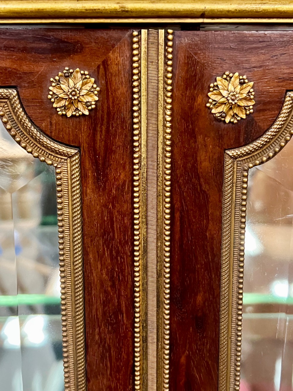 An antique French kingwood vitrine display cabinet featuring glazed double doors, gilt bronze ormolu mounts, glass shelves, a mirrored interior back, and a marble top. View XIII