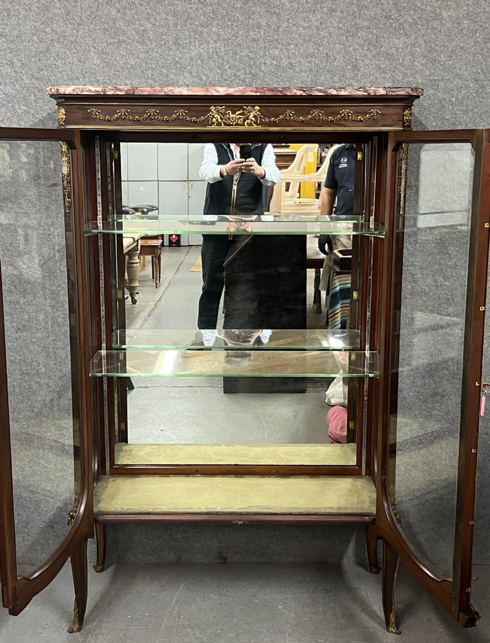 An antique French kingwood vitrine display cabinet featuring glazed double doors, gilt bronze ormolu mounts, glass shelves, a mirrored interior back, and a marble top. View XV