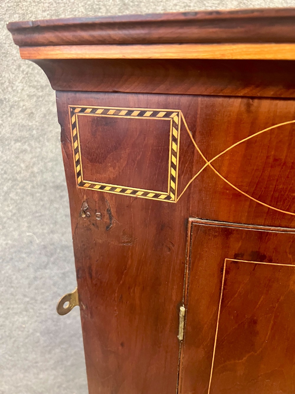 A George III mahogany bow-fronted hanging corner cabinet featuring double doors with fine stringing inlay and shield keyhole escutcheons. View III
