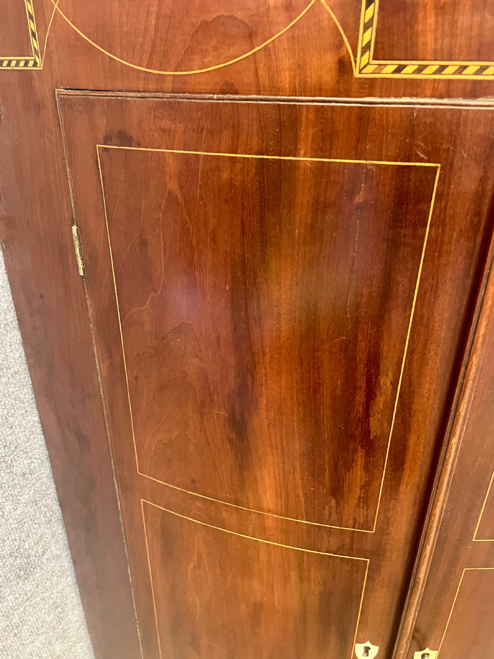 A George III mahogany bow-fronted hanging corner cabinet featuring double doors with fine stringing inlay and shield keyhole escutcheons. View IX