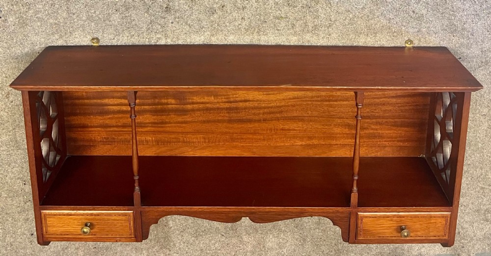 An Edwardian mahogany hanging wall shelf featuring turned spindle supports, fretwork side panels, and two small inlaid drawers with brass knobs. View II