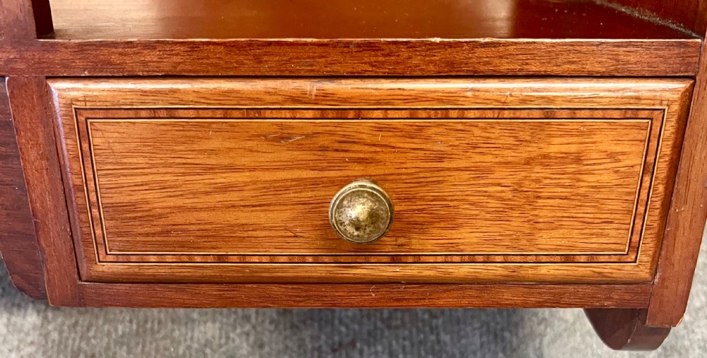 An Edwardian mahogany hanging wall shelf featuring turned spindle supports, fretwork side panels, and two small inlaid drawers with brass knobs. View VI