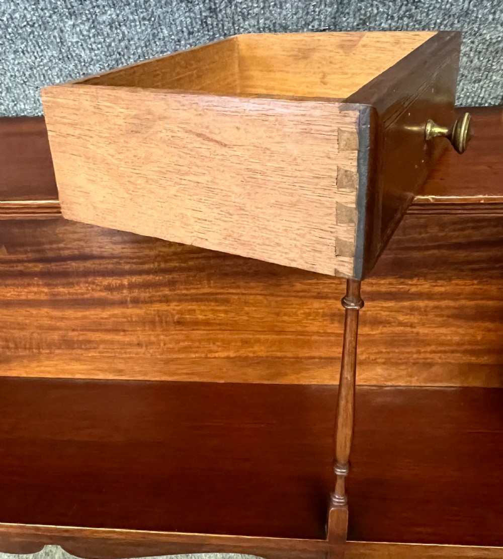 An Edwardian mahogany hanging wall shelf featuring turned spindle supports, fretwork side panels, and two small inlaid drawers with brass knobs. View VII