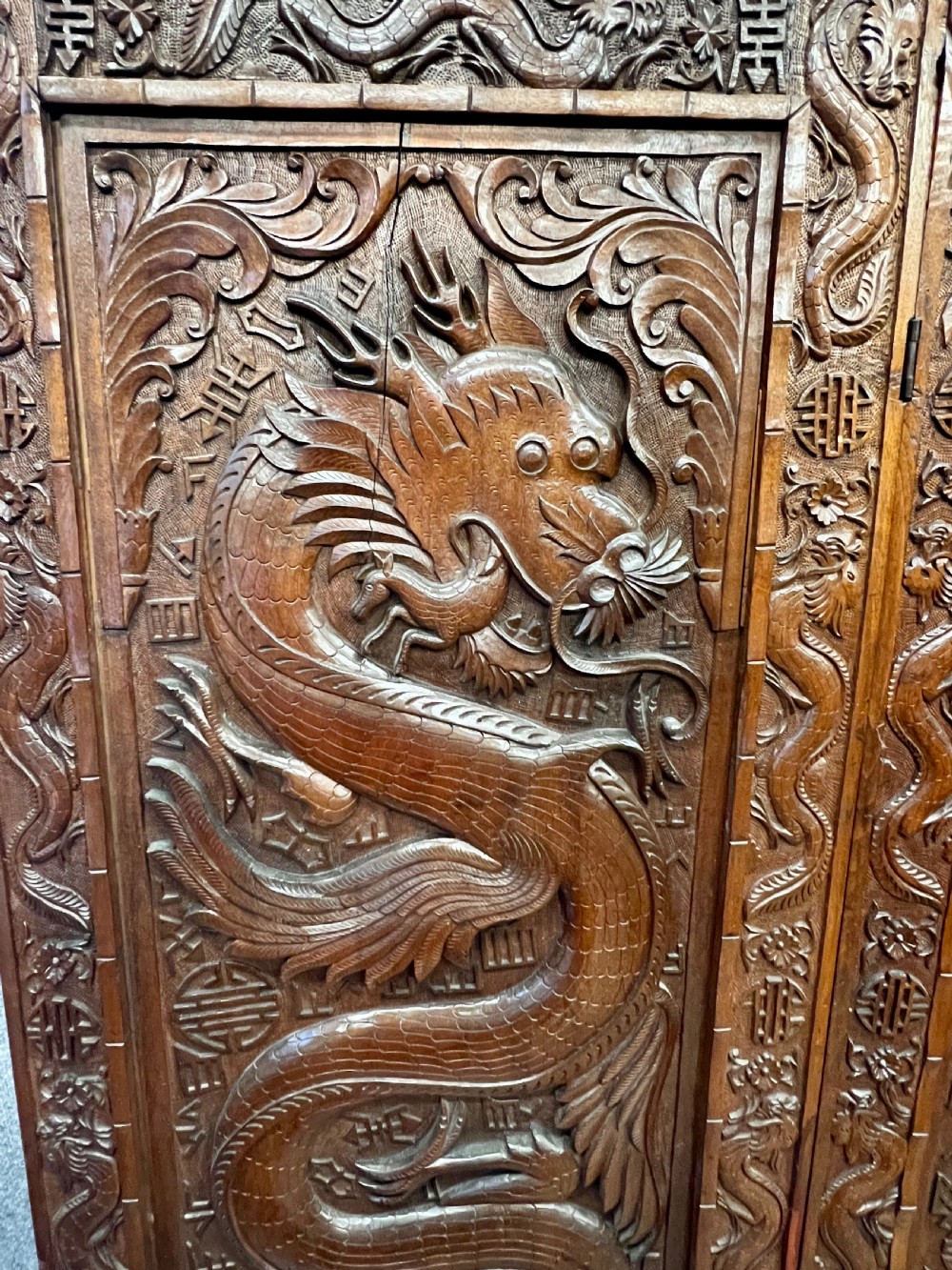 A four-panel carved hardwood folding room divider screen featuring relief dragon motifs and stepped top edges. View III