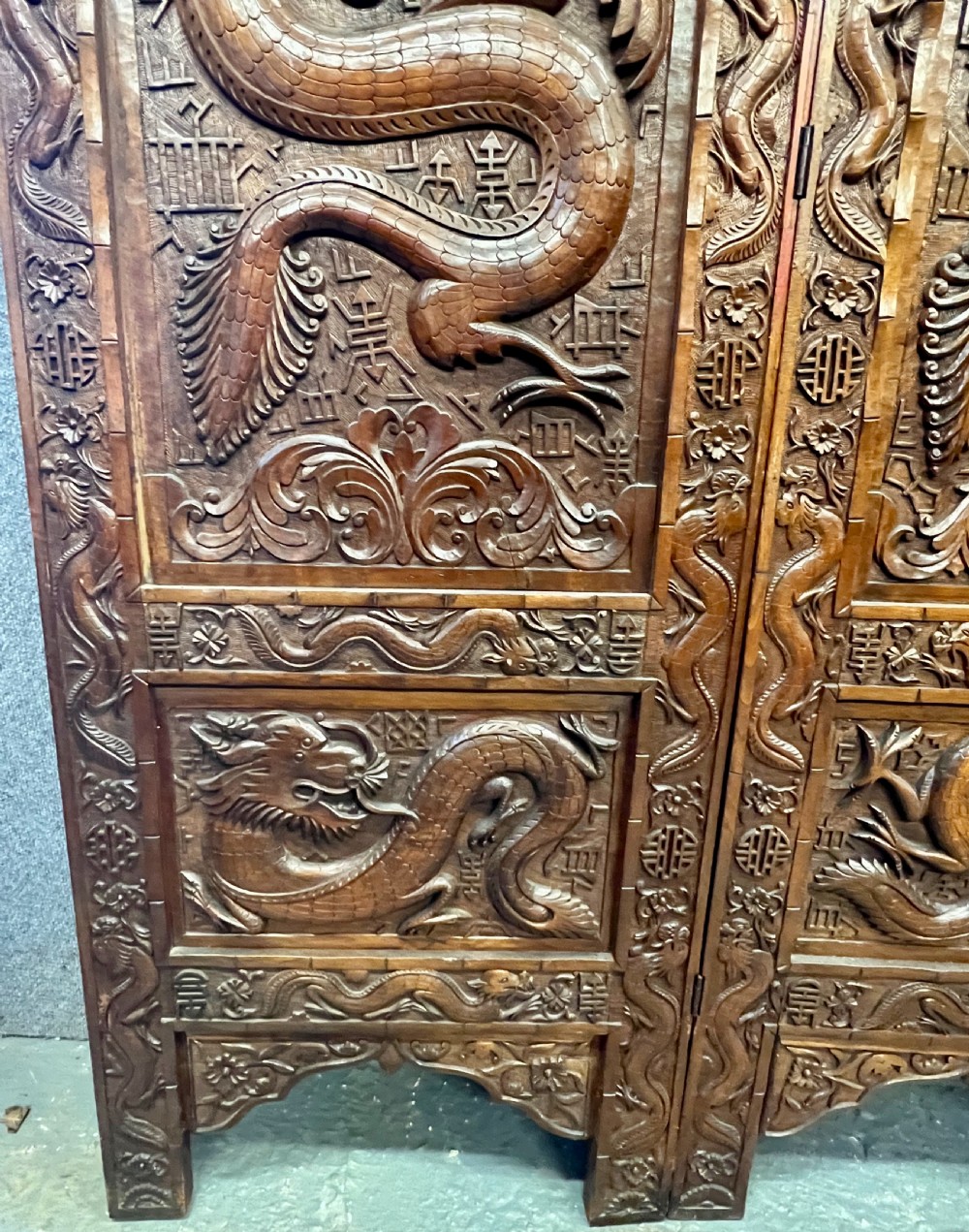 A four-panel carved hardwood folding room divider screen featuring relief dragon motifs and stepped top edges. View IV