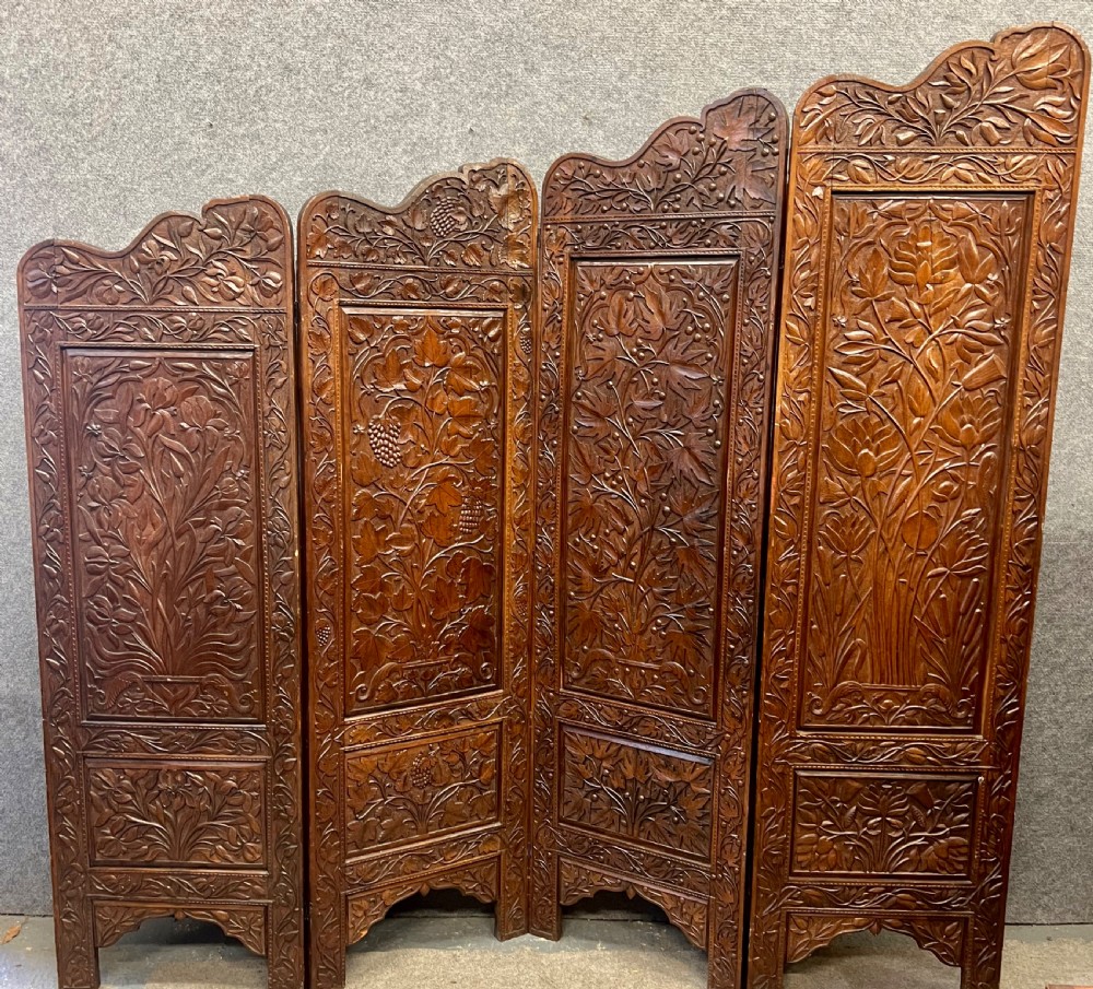 A four-panel carved hardwood folding room divider screen featuring relief dragon motifs and stepped top edges. View V