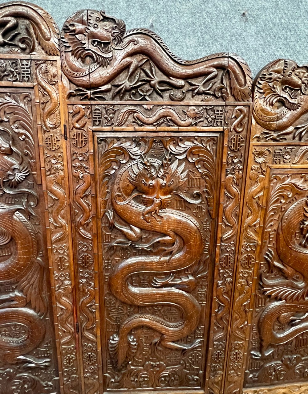 A four-panel carved hardwood folding room divider screen featuring relief dragon motifs and stepped top edges. View VI