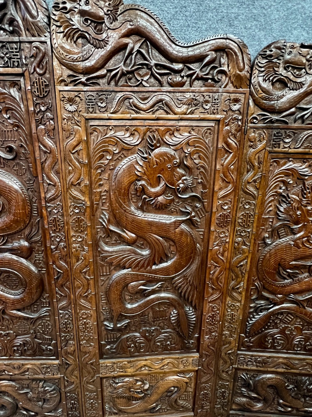 A four-panel carved hardwood folding room divider screen featuring relief dragon motifs and stepped top edges. View VII