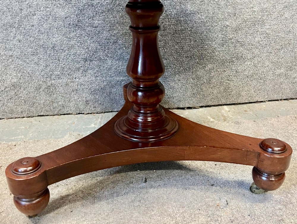 A circular mahogany revolving book mill table featuring a central turned column, four spindled book compartments, and a quadruped base. View V