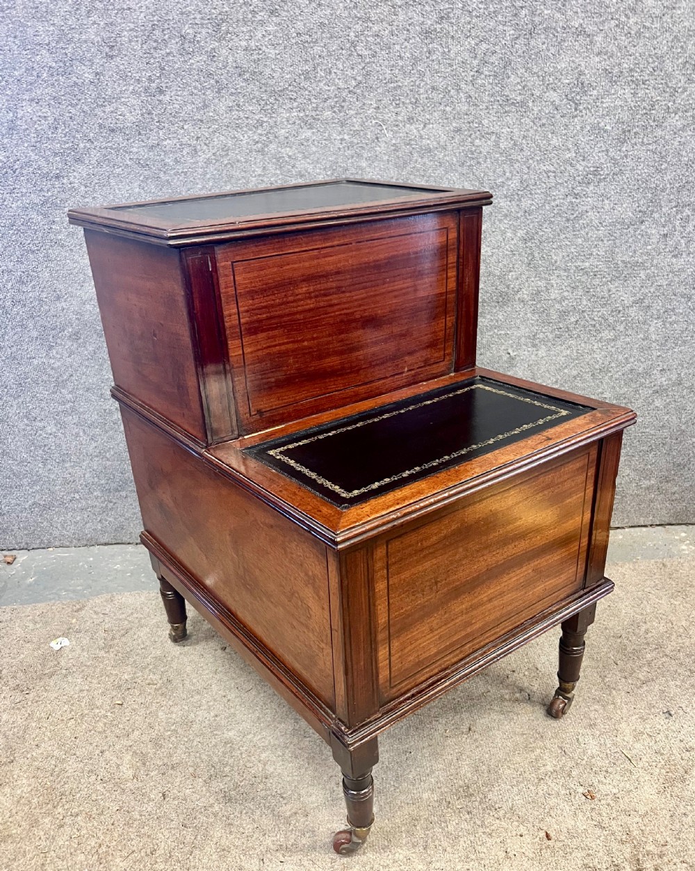 A Regency mahogany two-tier library step featuring dark leather inserts with gilt tooling, raised on turned legs with brass castors.