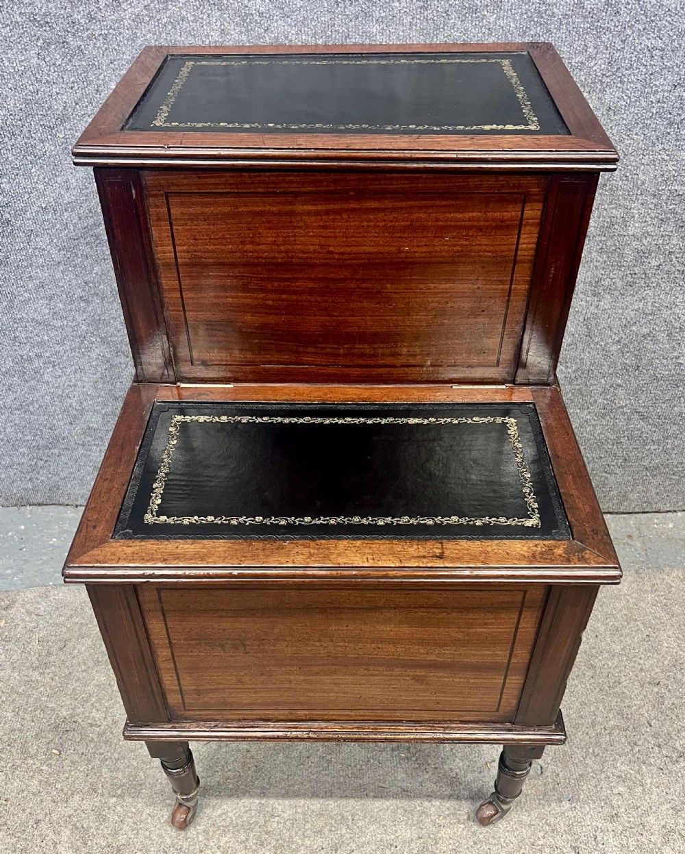 A Regency mahogany two-tier library step featuring dark leather inserts with gilt tooling, raised on turned legs with brass castors. View II