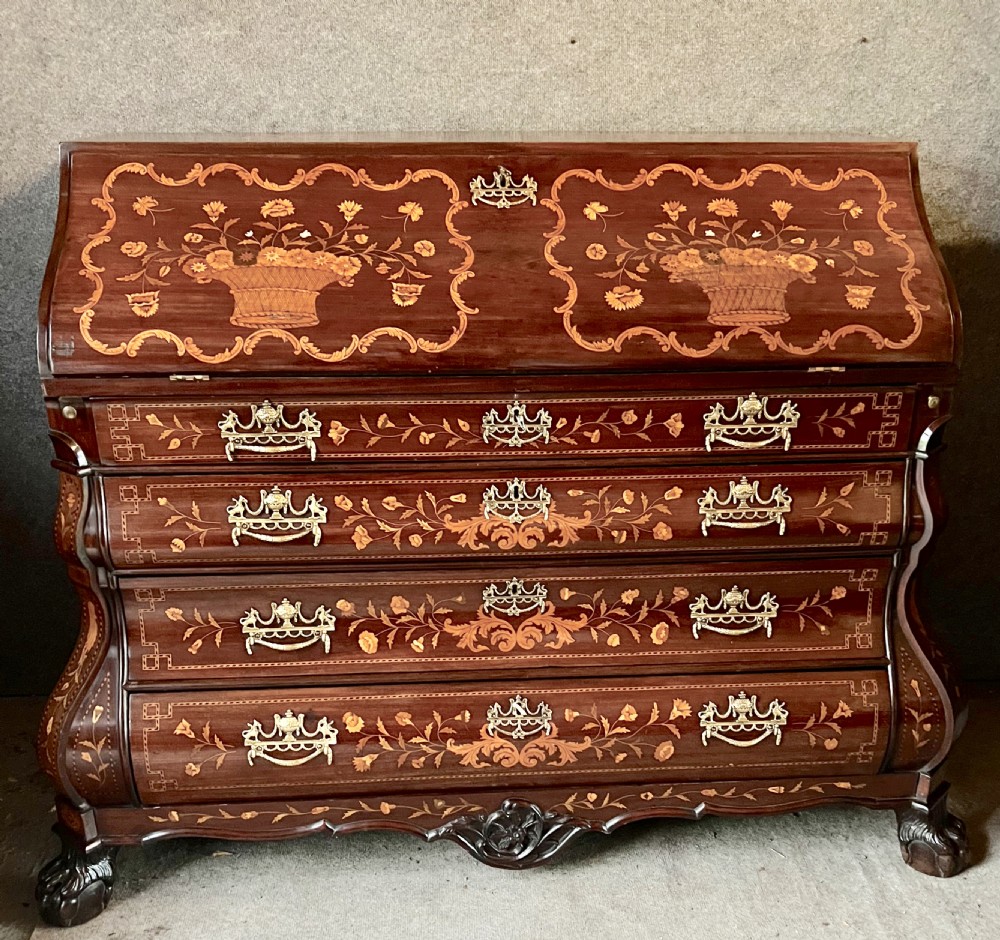 An antique Dutch marquetry writing bureau crafted from mahogany with detailed floral wood inlays, brass drop handles, and claw feet.