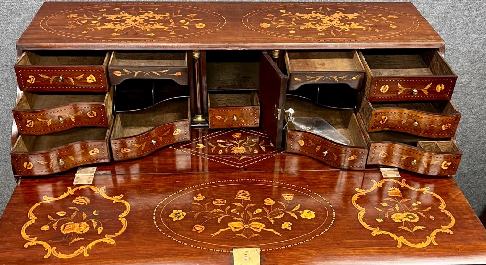 An antique Dutch marquetry writing bureau crafted from mahogany with detailed floral wood inlays, brass drop handles, and claw feet. View V