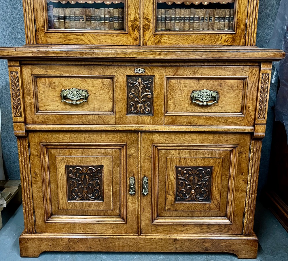 A two-tier Victorian pollard oak secretaire bookcase featuring upper glazed doors with books above a lower cabinet with carved relief panels. View II
