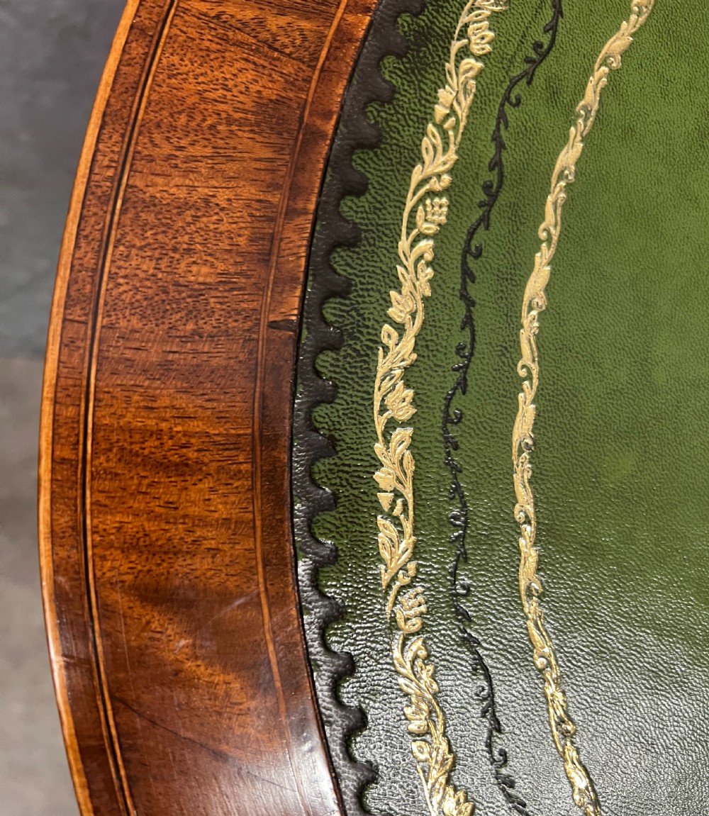 An Edwardian mahogany kidney-shaped desk with a green leather insert top, satinwood inlay, five drawers, and tapered legs on brass castors. View XI