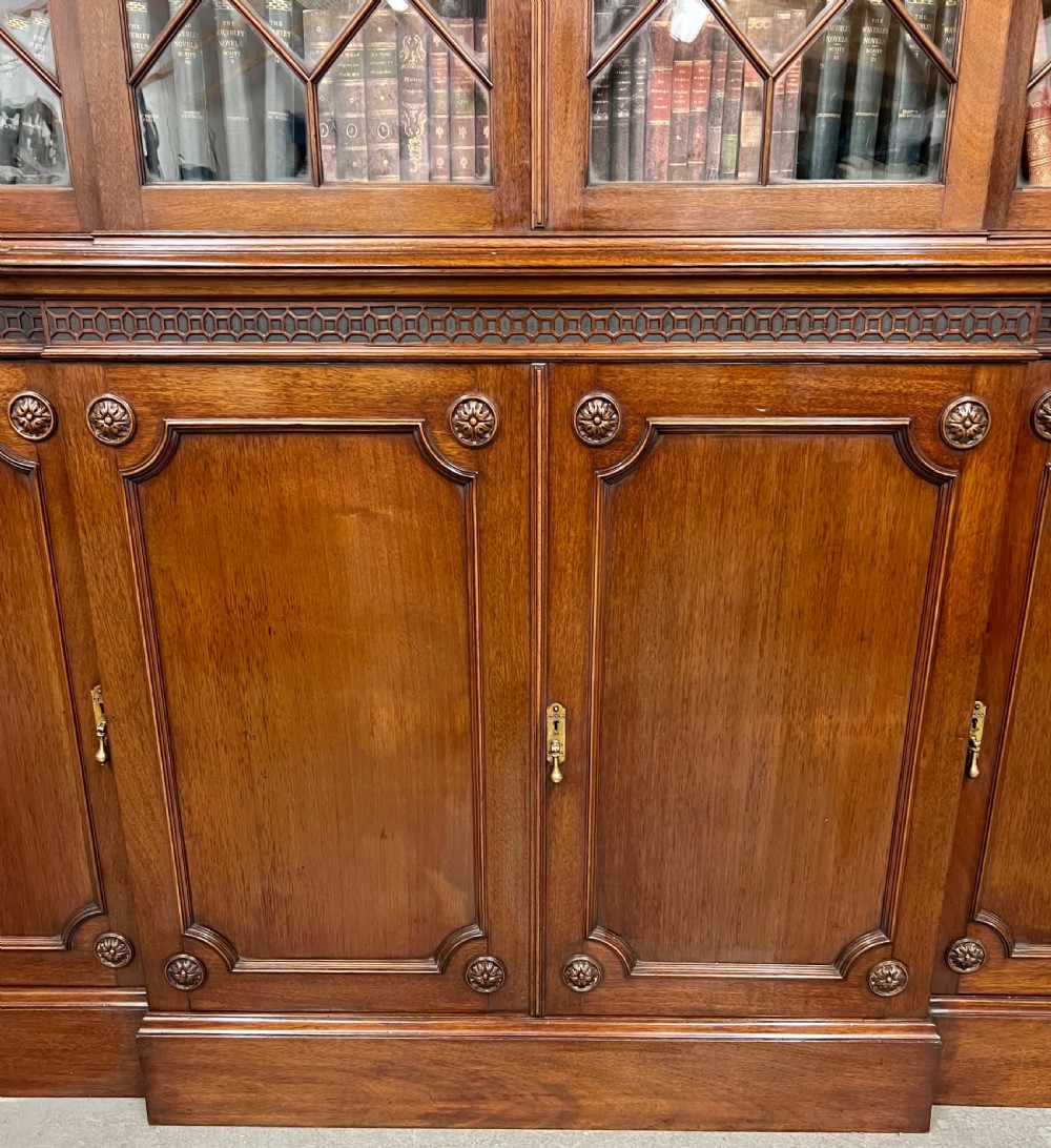 A large mahogany breakfront bookcase featuring four lattice-glazed upper doors above four panelled lower cupboard doors. View VII