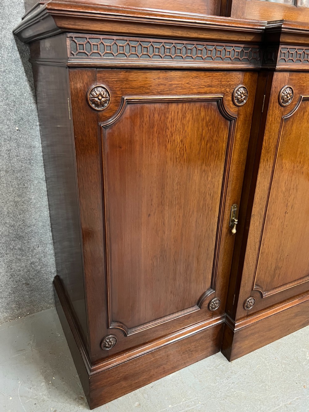 A large mahogany breakfront bookcase featuring four lattice-glazed upper doors above four panelled lower cupboard doors. View IX