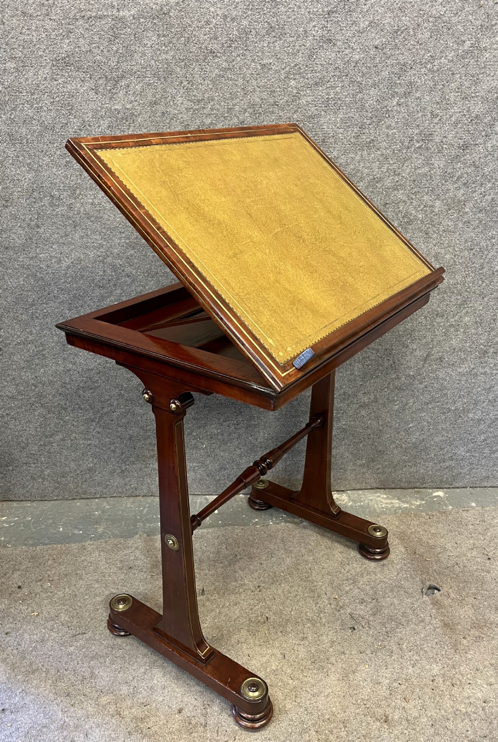 A Regency mahogany adjustable reading table with brass inlay and a gold tooled leather tilting top.