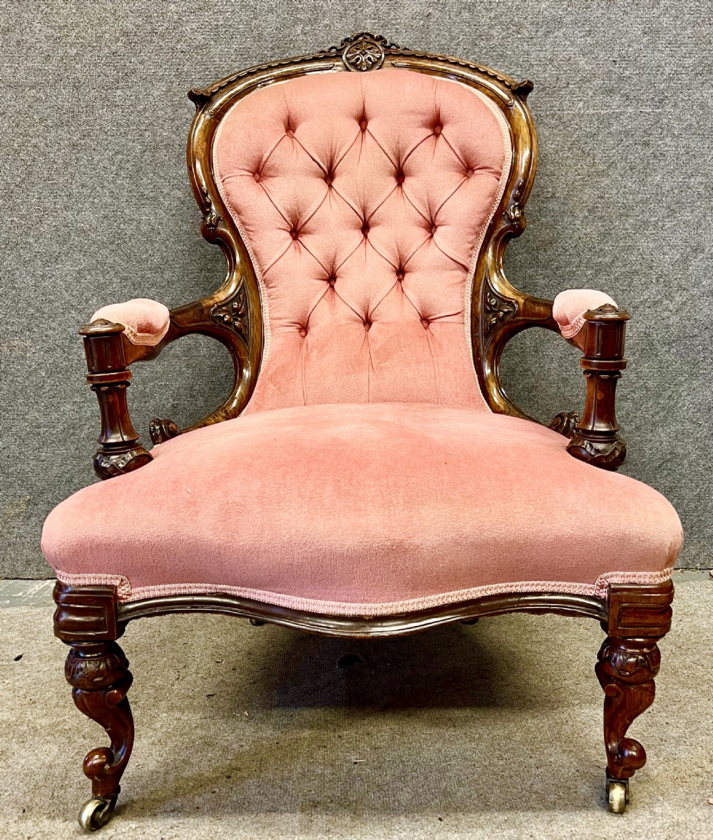 A Victorian open armchair crafted from carved dark walnut with button-backed rose pink velvet upholstery and brass castors. View III