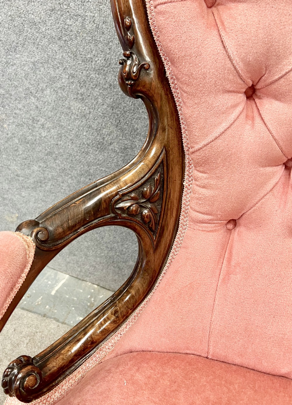 A Victorian open armchair crafted from carved dark walnut with button-backed rose pink velvet upholstery and brass castors. View VI