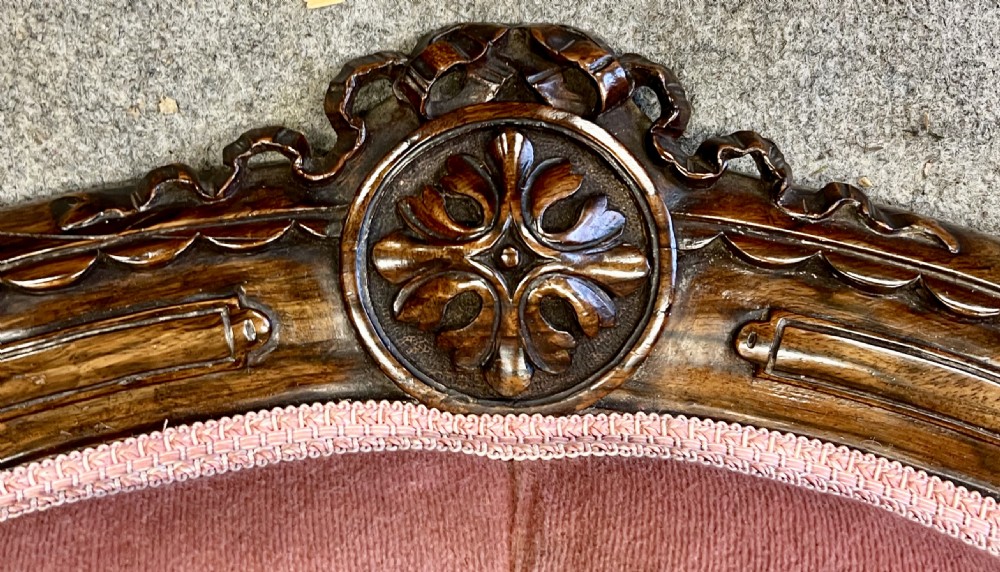 A Victorian open armchair crafted from carved dark walnut with button-backed rose pink velvet upholstery and brass castors. View X