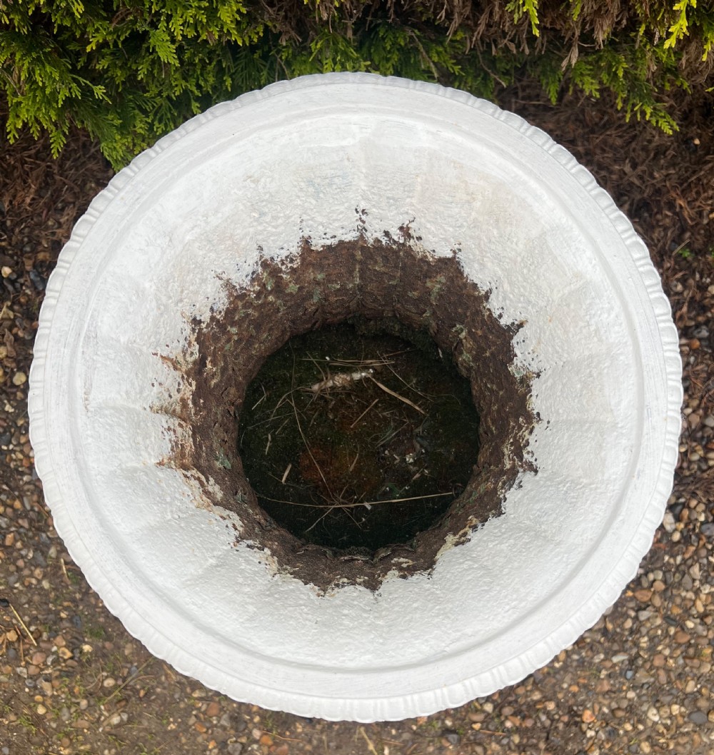 A white painted 19th-century cast iron garden urn featuring a fluted body atop a matching stepped pedestal stand. View IV