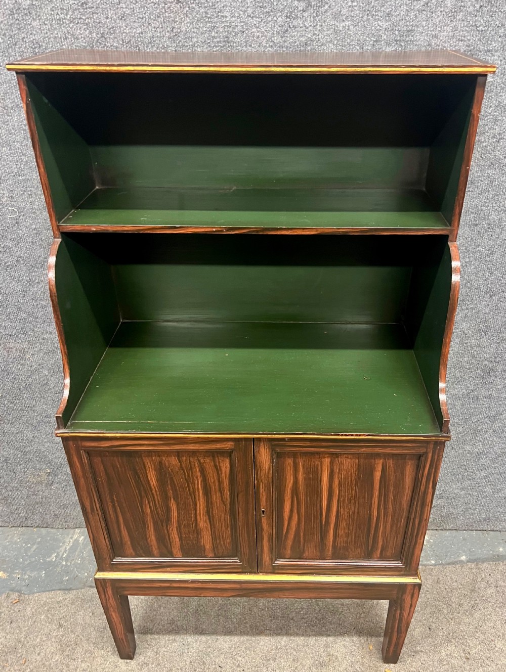 A Regency style dark wood waterfall bookcase featuring two open green-painted shelves over a double-door lower cabinet on tapered legs. View V