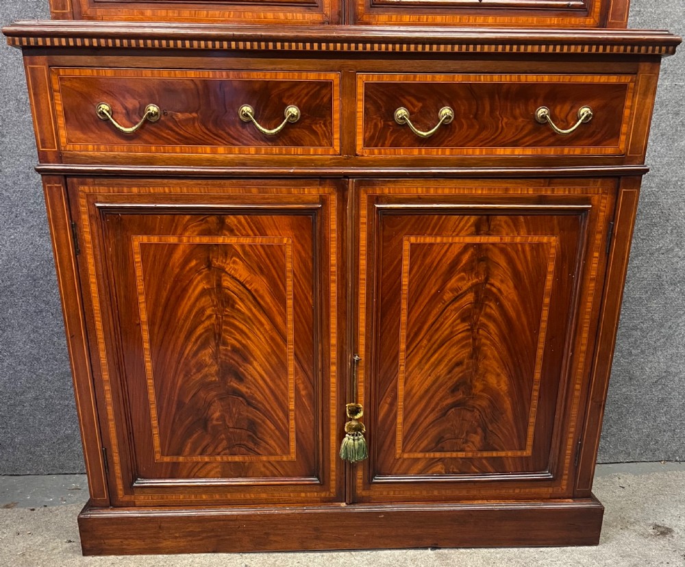 An Edwardian mahogany glazed bookcase with satinwood crossbanding, oval astragal door glazing, two drawers, and a double-door lower cupboard. View II
