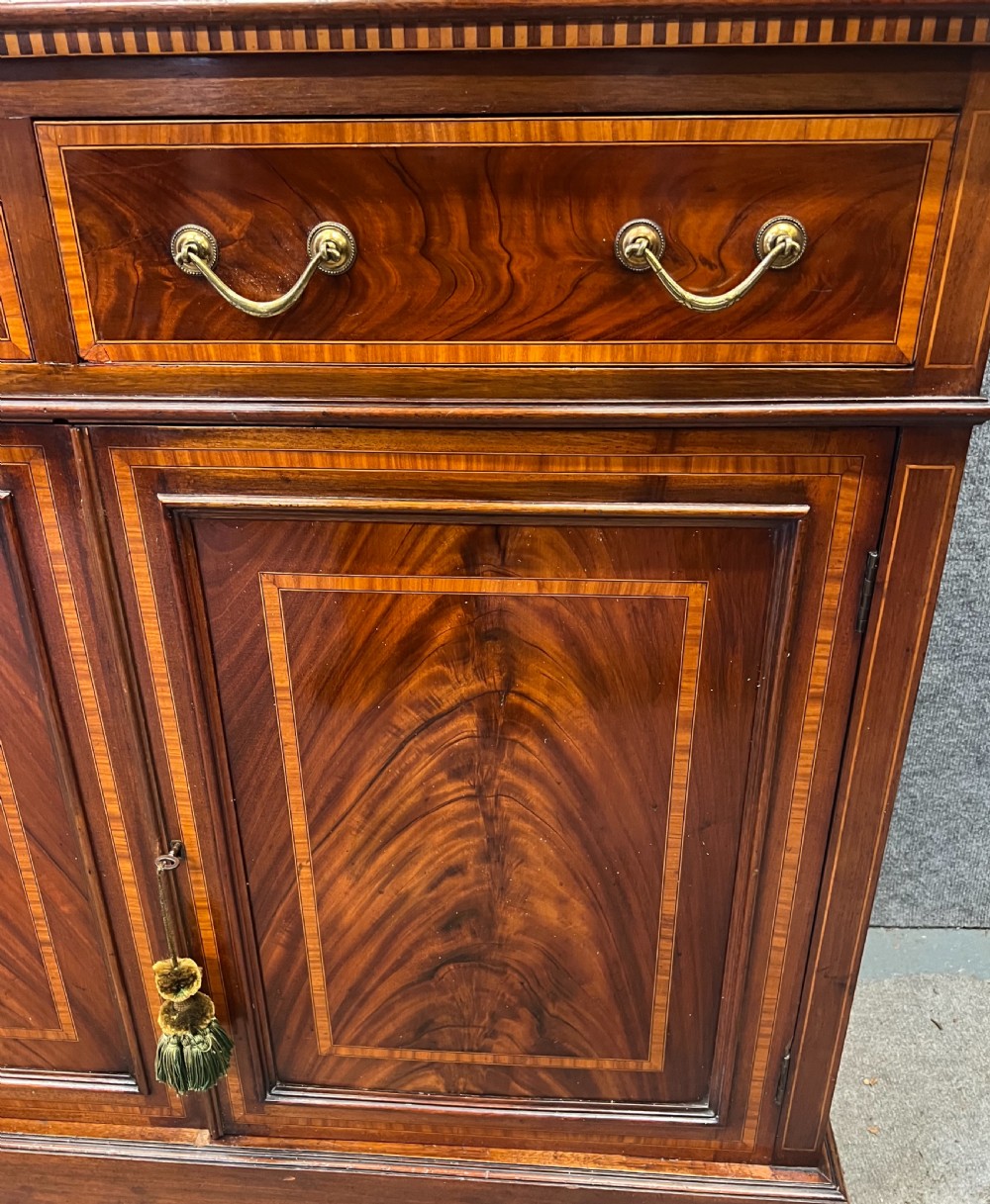 An Edwardian mahogany glazed bookcase with satinwood crossbanding, oval astragal door glazing, two drawers, and a double-door lower cupboard. View III