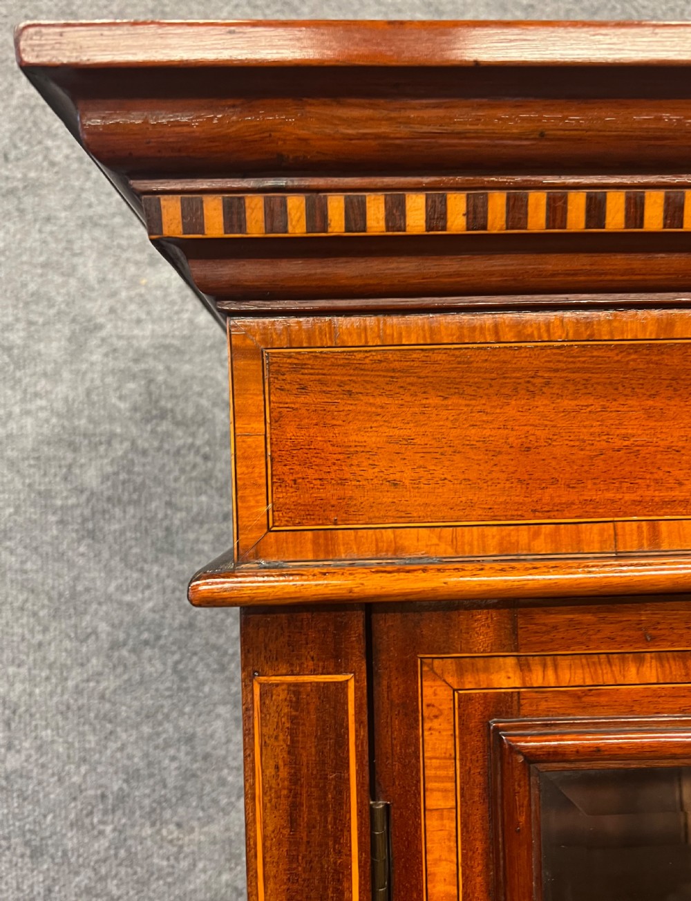 An Edwardian mahogany glazed bookcase with satinwood crossbanding, oval astragal door glazing, two drawers, and a double-door lower cupboard. View VI