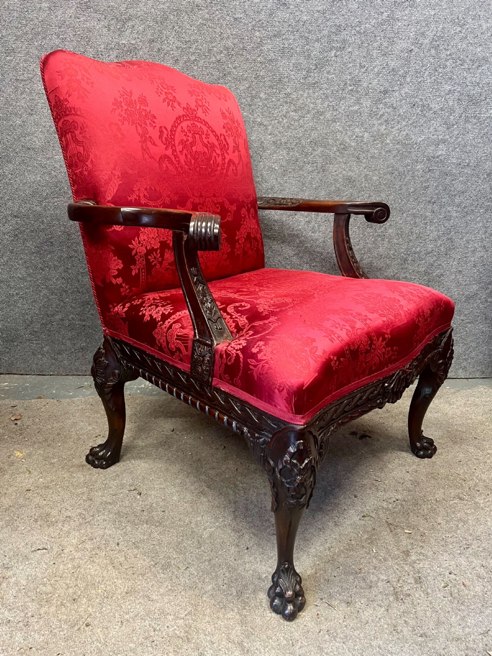 A 19th-century mahogany Gainsborough library chair upholstered in patterned crimson red damask, featuring carved cabriole legs and claw and ball feet. View VI