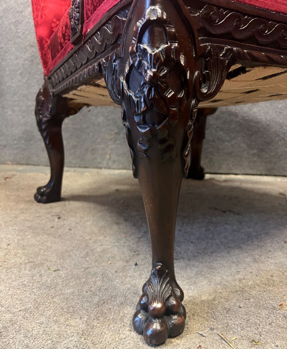 A 19th-century mahogany Gainsborough library chair upholstered in patterned crimson red damask, featuring carved cabriole legs and claw and ball feet. View VII