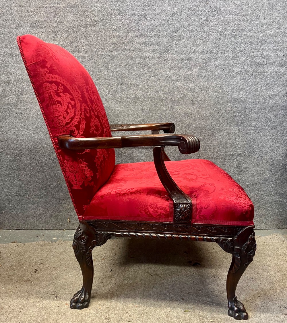 A 19th-century mahogany Gainsborough library chair upholstered in patterned crimson red damask, featuring carved cabriole legs and claw and ball feet. View IX