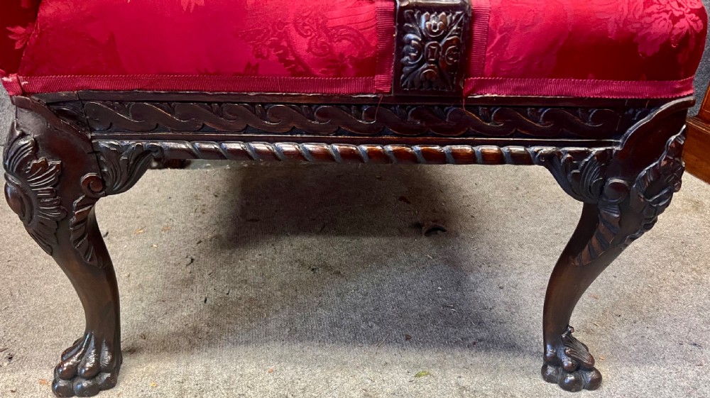 A 19th-century mahogany Gainsborough library chair upholstered in patterned crimson red damask, featuring carved cabriole legs and claw and ball feet. View X