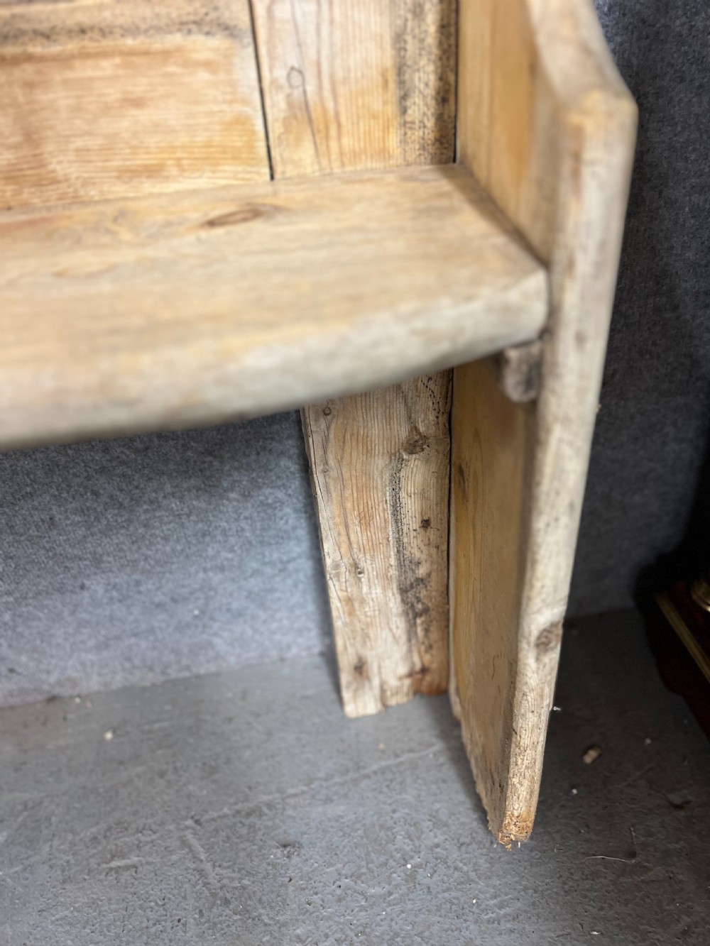 An antique light pine wooden settle featuring a high three-panel backrest, flat plank seat, and solid shaped side supports. View V